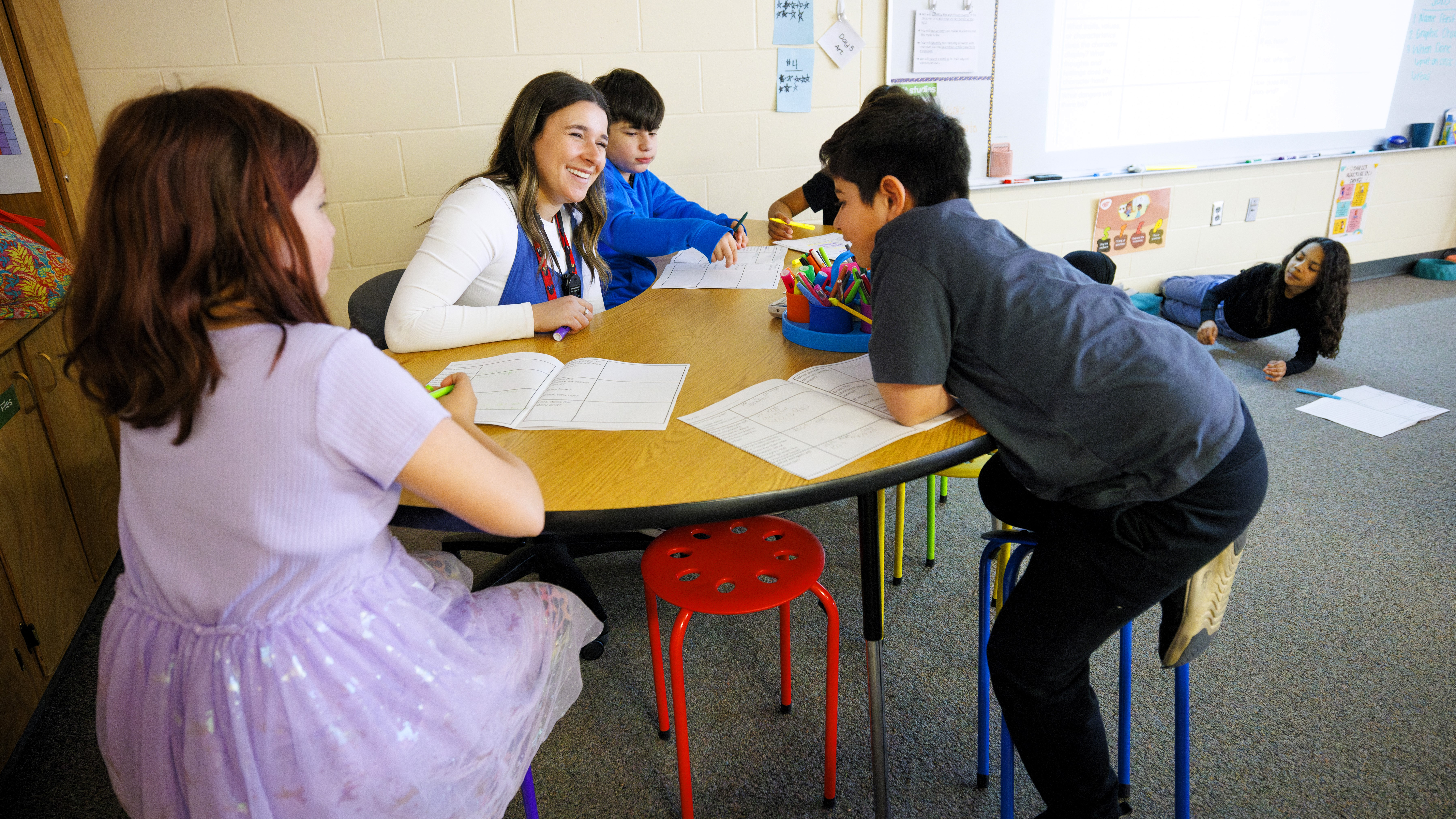 Teacher sitting with students in classroom.