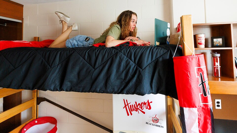 Student working on laptop in bed